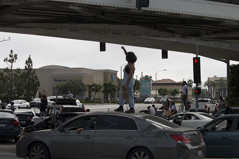 Protesters standing on top of cars in a street procession