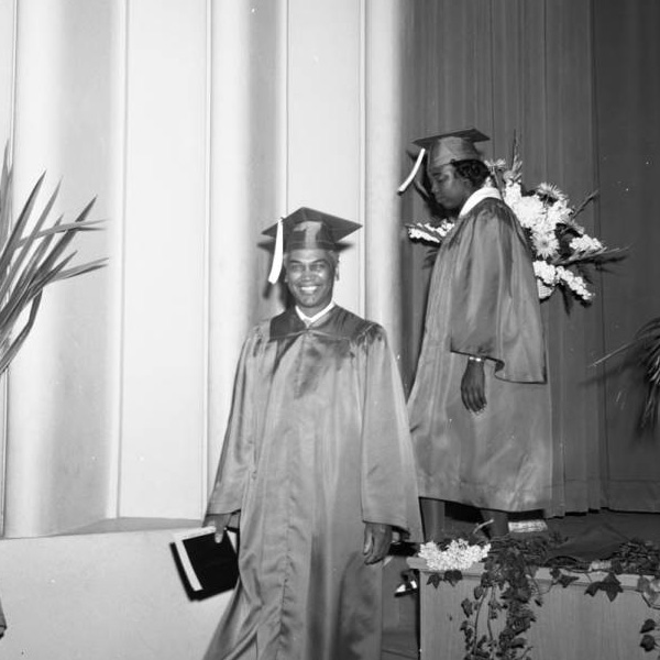 Charles Williams walking down a stage in graduation regalia.