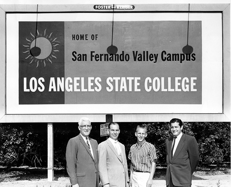 Four men standing in front of a sign