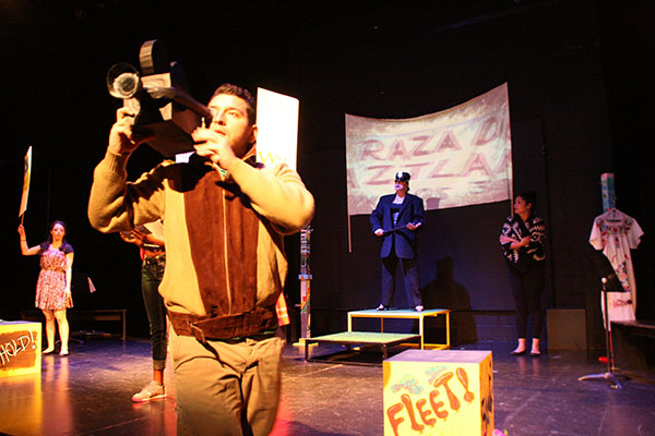 Man using an old-fashioned movie camera, other people in background