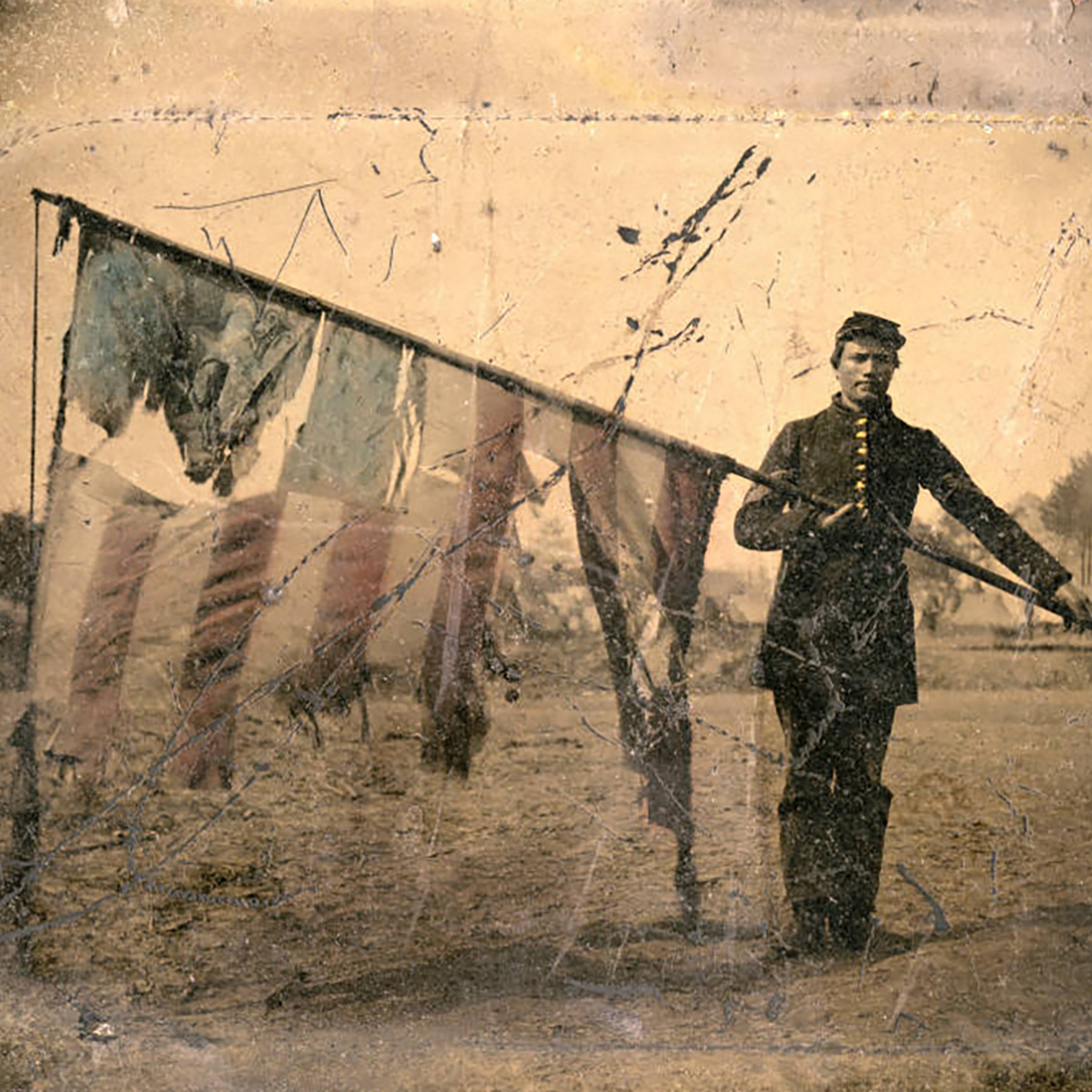 A soldier carrying a torn American flag.