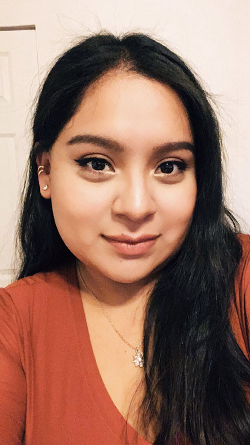 A photo of the podcaster, Lorena, wearing an orange shirt