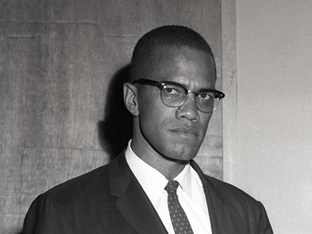 Man looking at camera in suit and glasses.