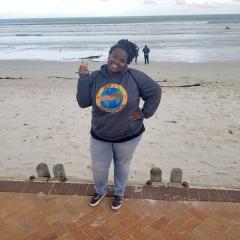 woman standing on a beach sidewalk wearing a sweatshirt commemorating the CSUN South Africa trip in 2019 