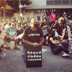 man holding a sign spelling Black Lives Matter in ASL