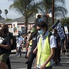 Masked marchers carrying signs including: BLACK LIVES MATTER
