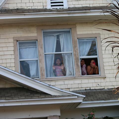 People watch from the second-story windows of a house