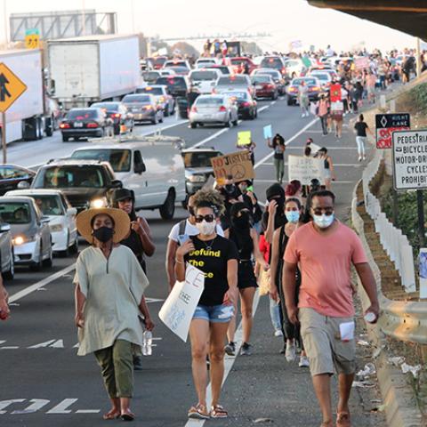 Four masked people leading others in a march along the freeway