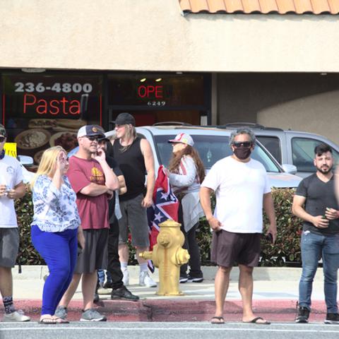 Group of people on the street, one holding a confederate flag.