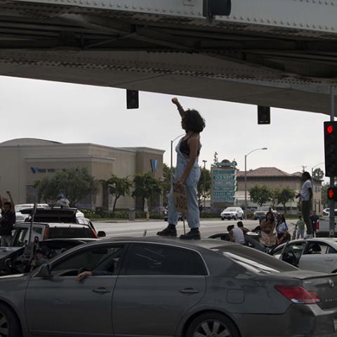 Protesters standing on top of cars in a street procession