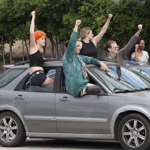 Protesters standing up through car windows with raised fists