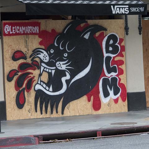 BLM and panther mural painted over a boarded storefront