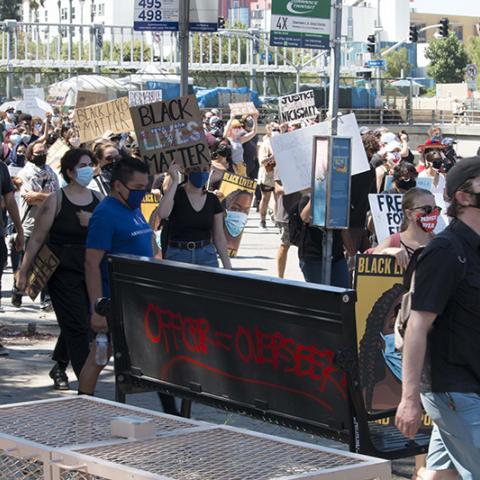 Group of masked people marching up the street holding handmade Black Lives Matter signs.