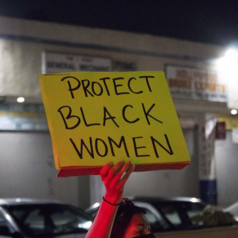 Hand holding handmade sign: PROTECT BLACK WOMEN