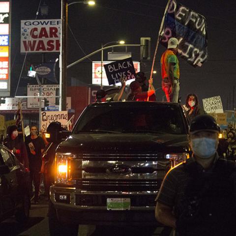  People marching with vehicles and signs: STILL NO JUSTICE STILL NO PEACE for BREONNA TAYLOR; BLACK LIVES MATTER; DEFUND DISARM DISMANTLE