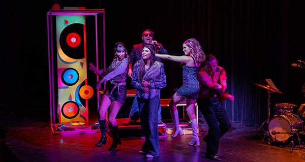 Group of people dancing and singing on a dimly illuminated stage