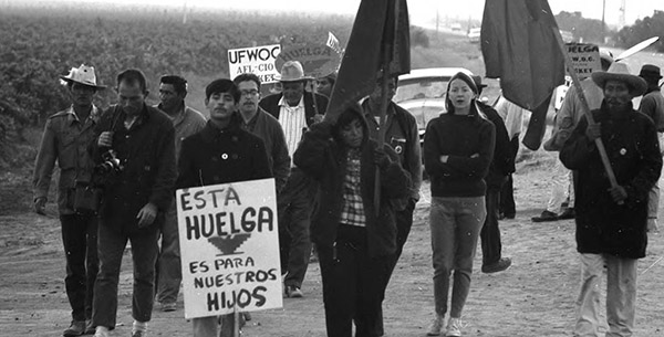 People walking along a dirt road with picket signs.