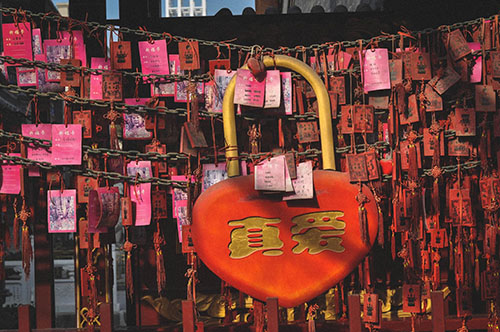 Pink and red lockets and wishes in Tianjin, China. One large heart locket hangs in the middle with the words 'true love' written on it in Chinese.