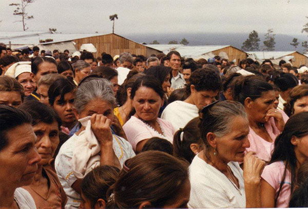 Crowd of people with houses in background.